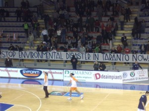 Lo striscione con la scritta in inglese "Ferma il disastro ambientale a Taranto ora"