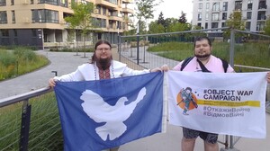 Artem Denysov e Yurii Sheliazenko nei pressi della palazzina colpita dal drone russo a Kiev con le bandiere del loro movimento pacifista. 
