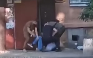 Un renitente è per terra e viene immobilizzato per strada dai reclutatori ucraini dopo una lotta corpo a corpo per fuggire