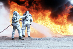 Due vigili del fuoco in tuta di prossimità durante un'esercitazione antincendio ad Aviano, 9 aprile 1990, nell'ambito dell'esercitazione "Salty Nation" che vide il 401° Tactical Fighter Wing schierato da Torrejón (Spagna). La didascalia originale non specifica quale agente estinguente sia stato utilizzato, quindi non possiamo affermare  che si trattasse di AFFF. Però in quegli anni l'AFFF fluorurata a base di PFOS era lo standard nelle basi aeree americane, senza alternative praticabili.