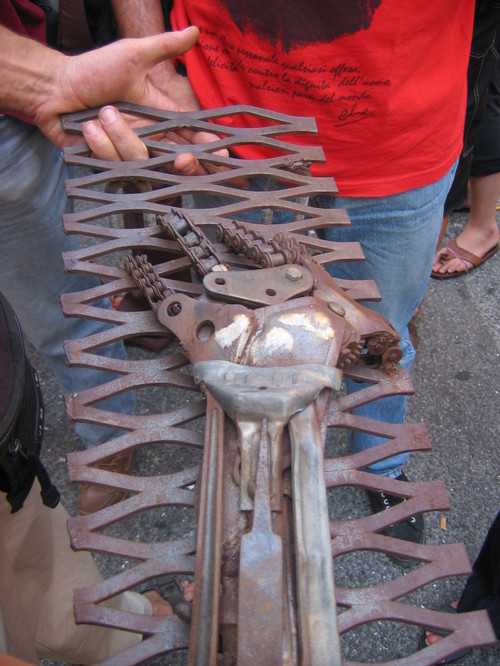 Genova, 20 luglio 2004, piazza Alimonda. Una scultura in ferro depositata sulla grata della chiesa di Nostra Signora del Rimedio dopo la morte di Carlo Giuliani. Dopo alcuni atti di vandalismo, la sc