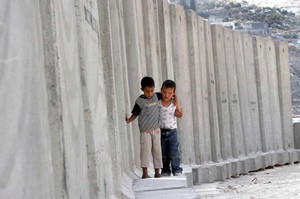 Due bambini palestinesi giocano vicino al muro costruito per separare Israele dalla Palestina.